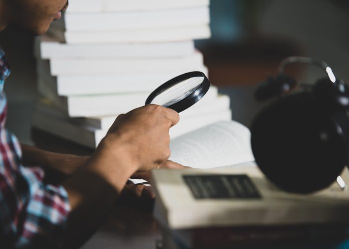 Educational theme: Close -up Student looking through a magnifying glass to  book